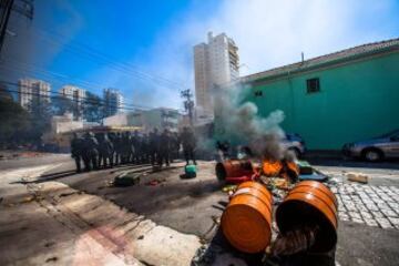 Miembros de la Policía brasileña dispersan a un grupo de manifestantes, durante la primera protesta contra el Mundial de fútbol Brasil 2014 registrada en Sao Paulo (Brasil), en el día en que comienza la competición. Cerca de 150 hombres de la Tropa de Choque de la Policía Militarizada del estado de Sao Paulo dispersaron a un grupo de 50 manifestantes que intentaba marchar por la avenida Radial Este, la principal vía de acceso al Arena Corinthians, el estadio de Sao Paulo en que se disputará el partido inaugural del Mundial.