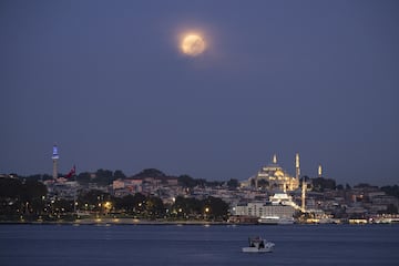 La superluna se eleva sobre la mezquita de Suleymaniye y la torre Beyazit durante un eclipse lunar parcial en Estambul, Turquía.