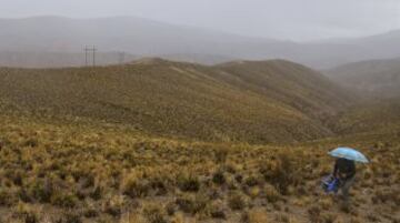 Un asistente se retira tras el paso de los competidores durante la quinta etapa entre Tupiza y Oruro.