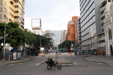 La gente viaja en motocicleta por una calle vacía, después de una noche repleta de explosiones en Caracas.