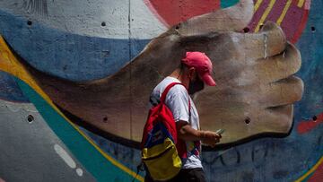 AME6931. CARACAS (VENEZUELA), 19/02/2021.- Un hombre camina frente a una pared decorada con un grafiti del artista venezolano Sim&oacute;n D&iacute;az hoy, en Caracas (Venezuela). EFE/ Miguel Guti&eacute;rrez