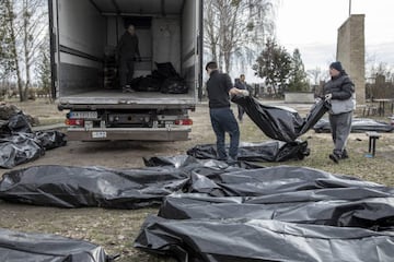 Workers load civilian dead bodies onto a truck.