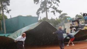 Los operarios de Roland Garros cubren con lonas las pistas por la lluvia