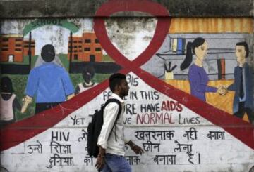 Un hombre camina junto a un mural decorado con motivos que hacen referencia al virus del sida durante el Día Mundial de esta enfermedad en Bombay, la India.