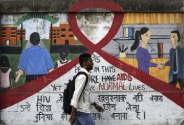 Un hombre camina junto a un mural decorado con motivos que hacen referencia al virus del sida durante el D¨ªa Mundial de esta enfermedad en Bombay, la India.