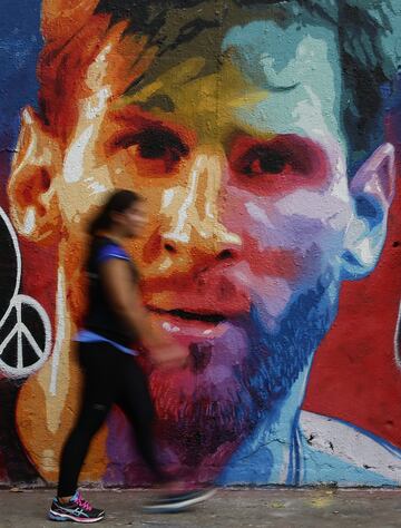 A woman walks past a graffiti artwork portraying FC Barcelona player Lionel Messi