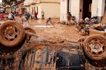 Un vehículo dañado es fotografiado mientras voluntarios y lugareños ayudan a limpiar lugares afectados por fuertes lluvias que provocaron inundaciones, en Paiporta.