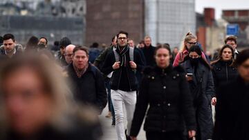 Pedestrians on their way to work cross the London Bridge in central London on January 27, 2022. - Commuters in England went back to work as coronavirus restrictions imposed to tackle the Omicron variant were lifted, with masks no longer required and vaccine passports shelved. (Photo by JUSTIN TALLIS / AFP)