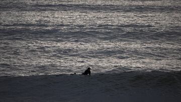 A surfer wades in the water during high surf in Los Angeles, California, U.S., December 24, 2024. REUTERS/Daniel Cole