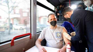 German Health Minister Karl Lauterbach (R) vaccinates a man against the novel coronavirus 