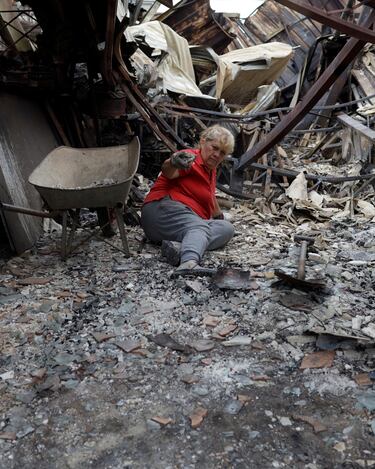Soledad Suárez en el suelo mientras busca objetos de valor en los restos quemados de su casa.