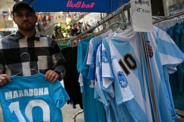 Un vendedor ambulante muestra camisetas del ídolo argentino con el Nápoles y con la selección de Argentina.