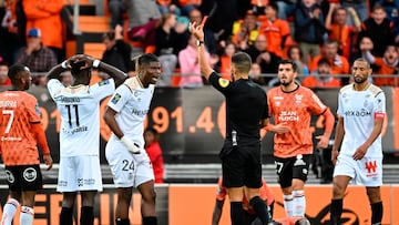 French referee Mathieu Vernice (C) shows the red card to Reims' Ivorian defender Emmanuel Agbadou (3rdL) during the French L1 football match between FC Lorient and Stade de Reims at the  Moustoir - Yves Allainmat Stadium in Lorient, western France on October 15, 2022. (Photo by Damien Meyer / AFP)