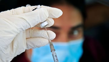 A nurse prepares a dose of the Pfizer-BioNTech vaccine against the COVID-19 for a health worker at a drive-through vaccination in Bogota, Colombia, on April 11, 2021. - Colombian health workers waited up to five hours on a seven-kilometer line in order to receive a vaccine against the coronavirus during the weekend. (Photo by DANIEL MUNOZ / AFP)