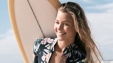 Imogen Caldwell, surfista, posando con su tabla de surf y su neopreno O'Neill.