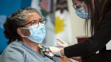 Nurse Shannon Lesch administers one of Illinois' first five Pfizer-BioNTech COVID-19 vaccinations outside of Chicago to Evelyn Tatum, who works in environmental services, at OSF Saint Francis Medical Center in downstate Peoria, Ill., Tuesday, Dec. 15, 2020. (Ashlee Rezin Garcia/Chicago Sun-Times via AP)