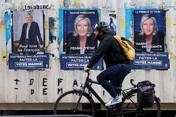 A man rides a bike in front of posters of Marine Le Pen.