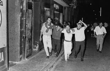 Personas trasladan aun herido durante las festividades de San Fermín en Pamplona, ​​​​España, en 1968.