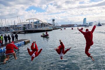 Varios participantes disfrazados de Papá Noel se lanzan al agua para participar en la 111º edición de la Copa Nadal.