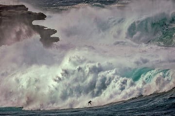 Un surfista monta una gran ola en Bondi Beach (S¨ªdney) bajo un espeso manto de nubes, sin que parezca preocuparle en absoluto el panorama que se observa a su alrededor, donde se pueden apreciar los fuertes oleajes y vientos que azotan la costa este de Australia. Una fotograf¨ªa de una belleza como solamente la naturaleza puede proporcionar.