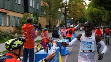 El atleta keniano Eliud Kipchoge recibe un bid¨®n de manos de su aguado Claus-Henning Schulke durante el marat¨®n de Berl¨ªn 2022.