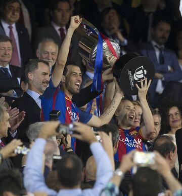 Busquets e Iniesta recogen el trofeo.