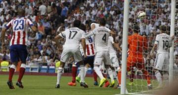 El portero del Real Madrid Iker Casillas (2d) no puede detener el balón disparado por el centrocampista del Atlético de Madrid Tiago y que ha supuesto el primer gol del partido de la tercera jornada de Liga de Primera División, disputado esta tarde en el estadio Santiago Bernabéu.