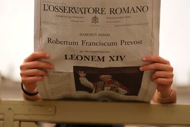 Un fiel lee un ejemplar del periódico vaticano L'Osservatore Romano con la noticia de la elección del papa León XIV mientras espera su aparición en el balcón central de la Basílica de San Pedro para su primera bendición dominical tras su elección.