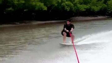 El surfista Italo Ferreira yendo a toda velocidad en aguas tranquilas y cogido de una cuerda con su tabla de surf.