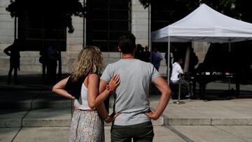 People listen as a music student plays on a grand piano during the &quot;Your city gets full of pianos&quot; initiative to promote music by bringing it to the people on the street, in Madrid, Spain, October 7, 2021. REUTERS/Susana Vera