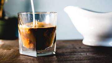Pouring milk and coffee in a glass with a blue background
