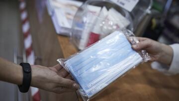 Archivo - Una farmacéutica enseña un paquete de mascarillas, en una imagen de archivo.