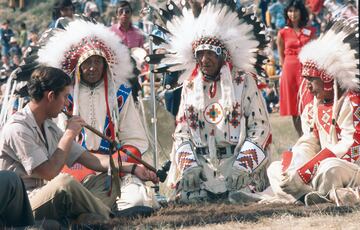 El prncipe de Gales fuma una pipa de la paz durante una ceremonia en la que se convirti en el Jefe Indio Red Crow durante una visita a Alberta, Canad, en 1977.  