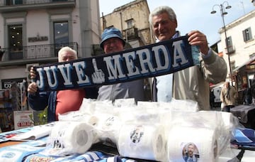 Vendors poses behind a scarf "Juve Merda" and toilet paper rolls with portraits of Juventus' Argentinian forward Gonzalo Higuain on March 23, 2017 in a street of Naples.