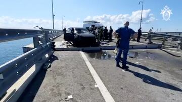 Russian investigators and emergency services' members gather near a destroyed car at the accident scene on the damaged section of a road following an alleged attack on the Crimea Bridge, that connects the Russian mainland with the Crimean peninsula across the Kerch Strait, in this still image taken from video released July 17, 2023. Investigative Committee of Russia/Handout via REUTERS ATTENTION EDITORS - THIS IMAGE WAS PROVIDED BY A THIRD PARTY. NO RESALES. NO ARCHIVES. MANDATORY CREDIT. WATERMARK FROM SOURCE.