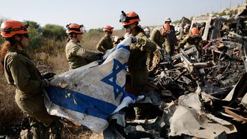 Israeli soldiers from the Home Front Command recover an Israeli flag as they search damaged cars for human remains and other evidence, following the deadly October 7 attack by Hamas gunmen from the Gaza Strip,?on a field near Netivot in southern Israel, November 1, 2023. REUTERS/Amir Cohen