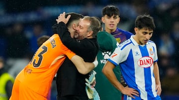 El entrenador del Barcelona Hans-Dieter Flick (c) abraza a Joan García al finalizar el partido de la jornada 18 de LaLiga entre el RCD Espanyol y el FC Barcelona, este sábado en el RCDE Stadium.