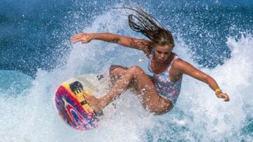 Chica surfeando con un bañador de los años 80s y una tabla de surf colorida, en la película Girls Can't Surf.