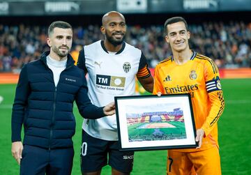 Los capitanes momentos antes del encuentro. Lucas Vzquez recibe de  manos de Jos Luis Gay y Dimitri Foulquier un cuadro de la bandera de la Comunidad Valenciana que el Real Madrid despleg en su estadio en el momento de la DANA y posteriormente entreg al Valencia.