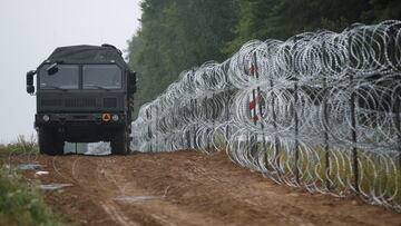 FILE PHOTO: A view of a vehicle next to a fence built by Polish soldiers on the border between Poland and Belarus near the village of Nomiki, Poland August 26, 2021. REUTERS/Kacper Pempel/File Photo