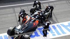 Los mec&aacute;nicos de McLaren empujan el coche de Fernando Alonso hacia el box.