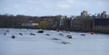 The Cambridge (near C) crew lead Oxford crew as they row in to toward the finish line with the flotilla following in the annual men's boat race between Oxford and Cambridge University on the River Thames in London on March 27, 2016. / AFP PHOTO / NIKLAS HALLE'N