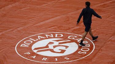 (FILES) In this file photo taken on June 8, 2019, a groundstaff member walks on the cover across the court surface as rain falls during the men's singles semi-final match between Austria's Dominic Thiem and Serbia's Novak Djokovic on day fourteen of The R