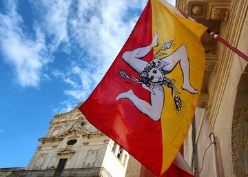 Conocida como la Trinacria. En el centro de la bandera aparece una variante del trisquel consta de tres piernas flexionadas que representan la forma de la isla y en el centro la cabeza de Medusa con alas y tres espigas de trigo que representan la prosperidad y los frutos de la tierra.