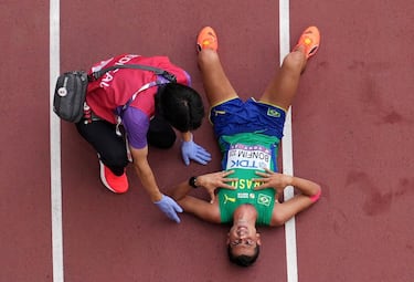 Caio Bonfim de Brasil reacciona mientras un médico observa después de cruzar la línea para ganar la medalla de plata en la marcha de 35 km masculina.