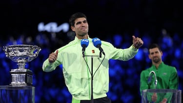 Carlos Alcaraz celebra su victoria en la ceremonia de premiación del Open Australia con Novak Djokovic a su espalda.