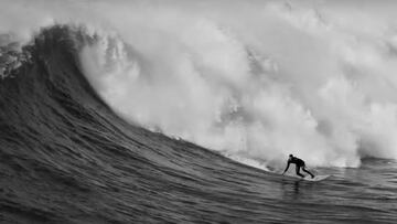 Un surfista llega al bottom de una ola gigante que rompe pisándole los talones en la playa de Meñakoz (País Vasco), en blanco y negro, durante la temporada de invierno 2020-2021.