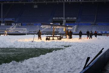 Operarios del club, ayudados con l¨¢mparas LED, eliminan la nieve del c¨¦sped del estadio de Mendizorroza.