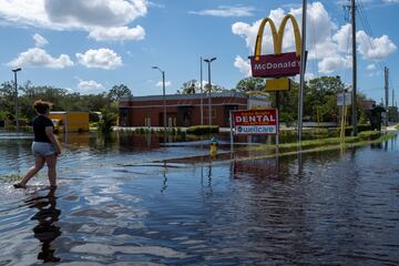 La gente camina sobre el agua mientras las carreteras y los comercios se inundan por la crecida del río Anclote durante la recuperación del huracán Milton el 11 de octubre de 2024 en New Port Richey, Florida.