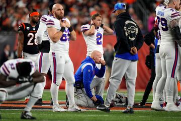 El entrenador en jefe de los Buffalo Bills, Sean McDermott, se arrodilla mientras, Damar Hamlin (3), es atendido en el campo después de una colisión.